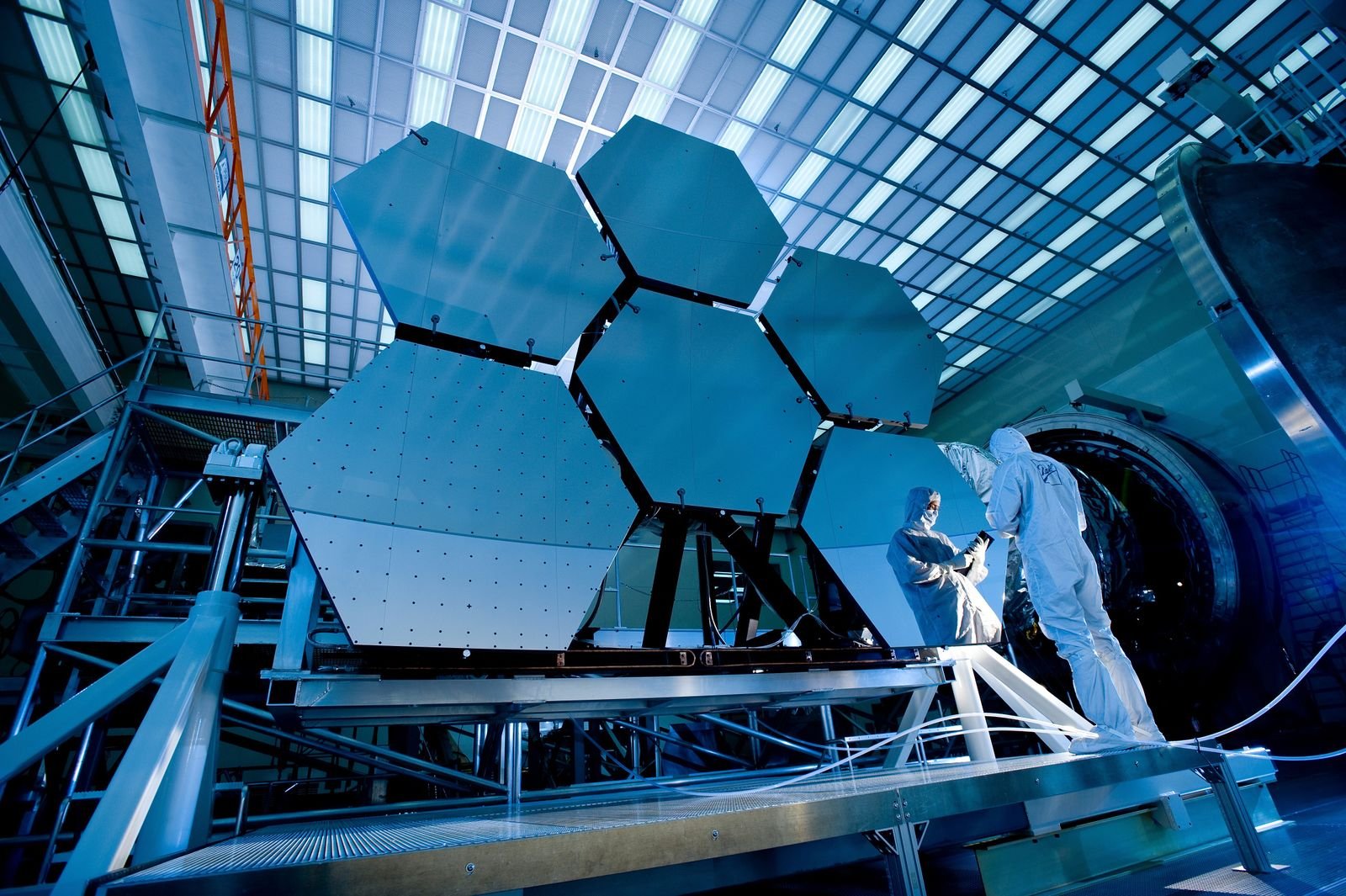 Technicians in a large clean facility working beside a hexagonal precision assembly